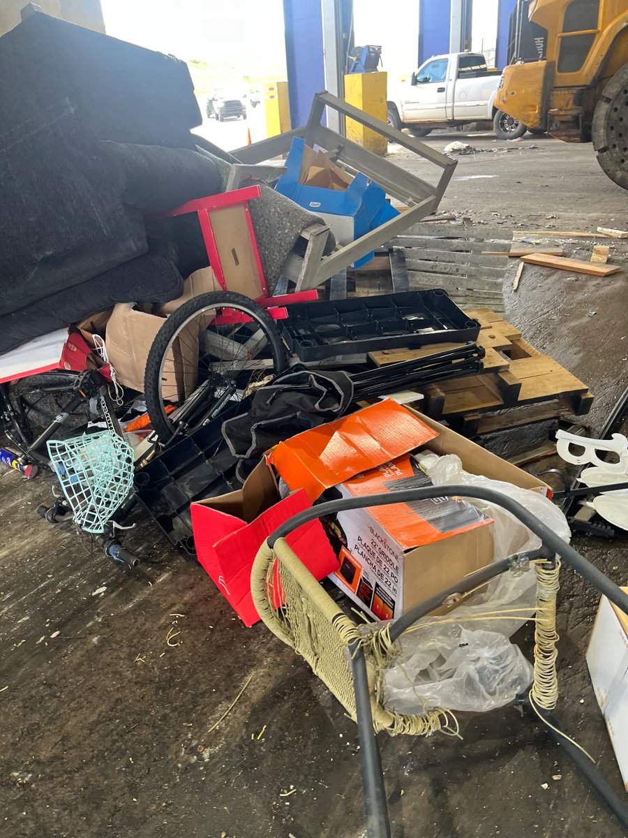 Scattered household junk, bags and old equipment on the concrete floor of a disposal building